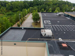 Aerial view of flat asphalt roofs surrounded by green trees