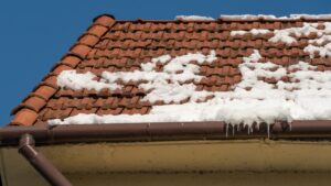 Home orange tile roof with snow and ice on it